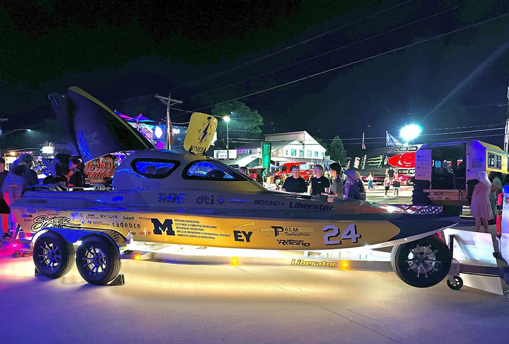 Maize and blue electric boat out at night under the lights